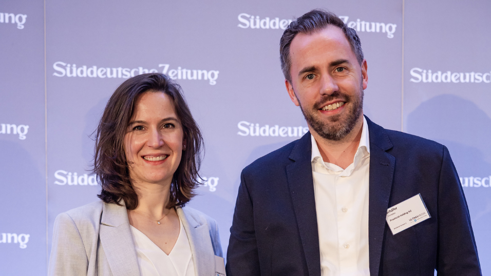 Foto von zwei Teilnehmende vor dem Bühnenhintergrund beim SZ-Versicherungstag 2026